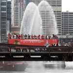 
              Chicago Blackhawks players, with the Stanley Cup, ride in an open top bus across the Monroe Street Bridge over the Chicago River during a parade celebrating the NHL hockey club's Stanley Cup championship, Thursday, June 18, 2015, in Chicago. (AP Photo/Kiichiro Sato)
            