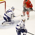 
              Tampa Bay Lightning goalie Andrei Vasilevskiy, left, deflects a puck as teammate Jason Garrison (5) and Chicago Blackhawks' Brandon Saad (20) watch during the third period in Game 4 of the NHL hockey Stanley Cup Final Wednesday, June 10, 2015, in Chicago. (AP Photo/Charles Rex Arbogast)
            