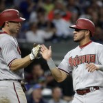 Arizona Diamondbacks' Paul Goldschmidt, left, greets David Peralta as the two score on a single by Chris Owings against the Seattle Mariners in the sixth inning of a baseball game, Tuesday, July 28, 2015, in Seattle. (AP Photo/Elaine Thompson)
