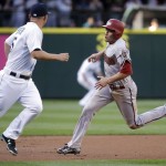 Arizona Diamondbacks' A.J. Pollock, right, races past Seattle Mariners third baseman Kyle Seager on his way to score in the first inning of a baseball game Tuesday, July 28, 2015, in Seattle. (AP Photo/Elaine Thompson)
